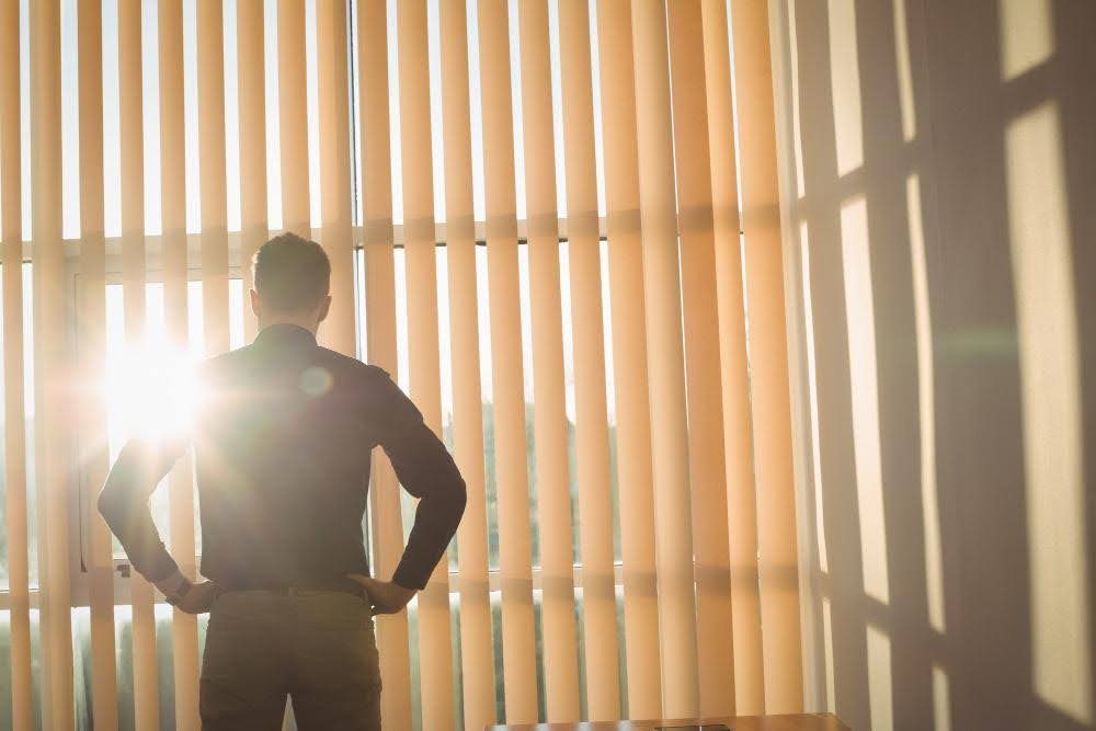 A person looking outside through a window in bright sunlight.