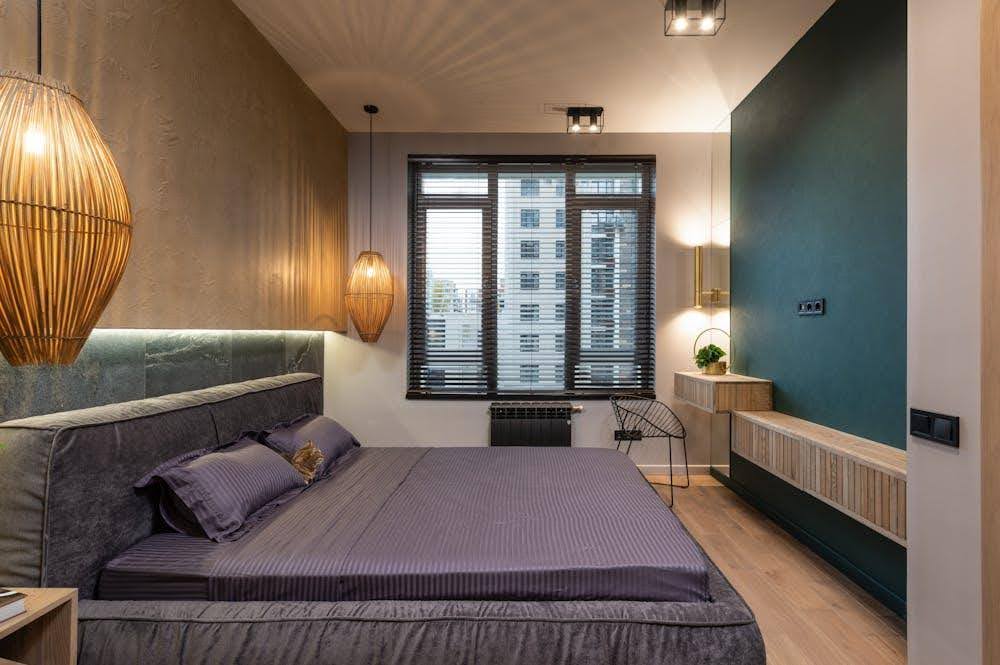 A modern bedroom featuring large windows fully covered by sleek motorized blinds.