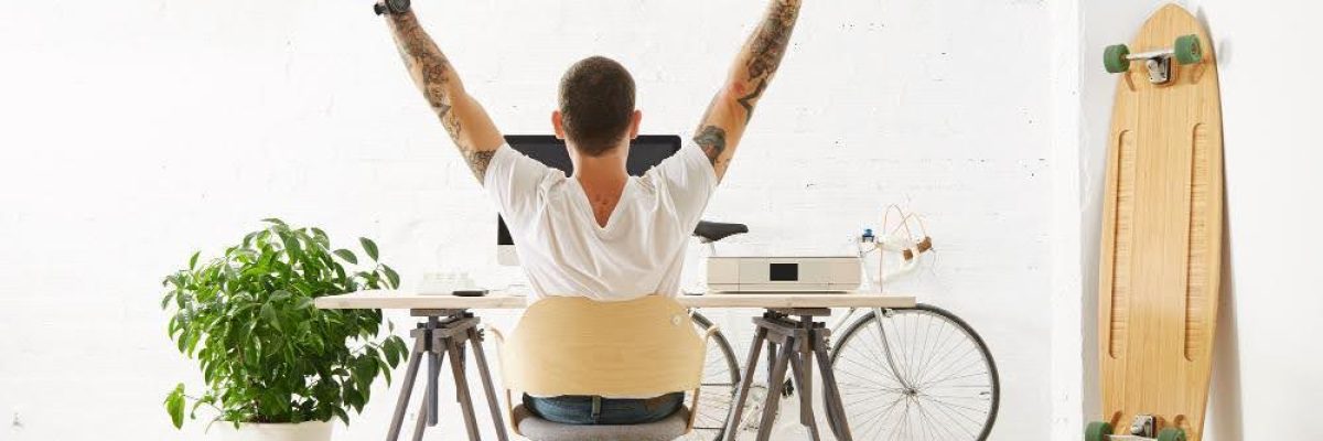A man with arms raised, sitting at a desk in a room cooled without AC.