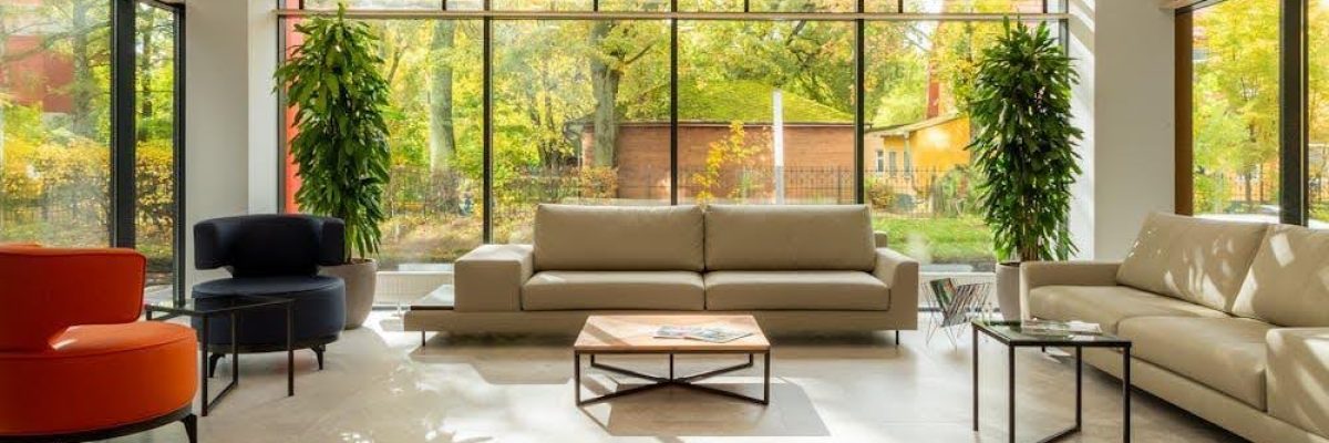 A modern, stylish living room with large windows partially covered by electric blinds.