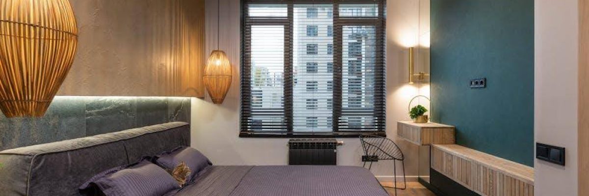 A modern bedroom featuring large windows fully covered by sleek motorized blinds.